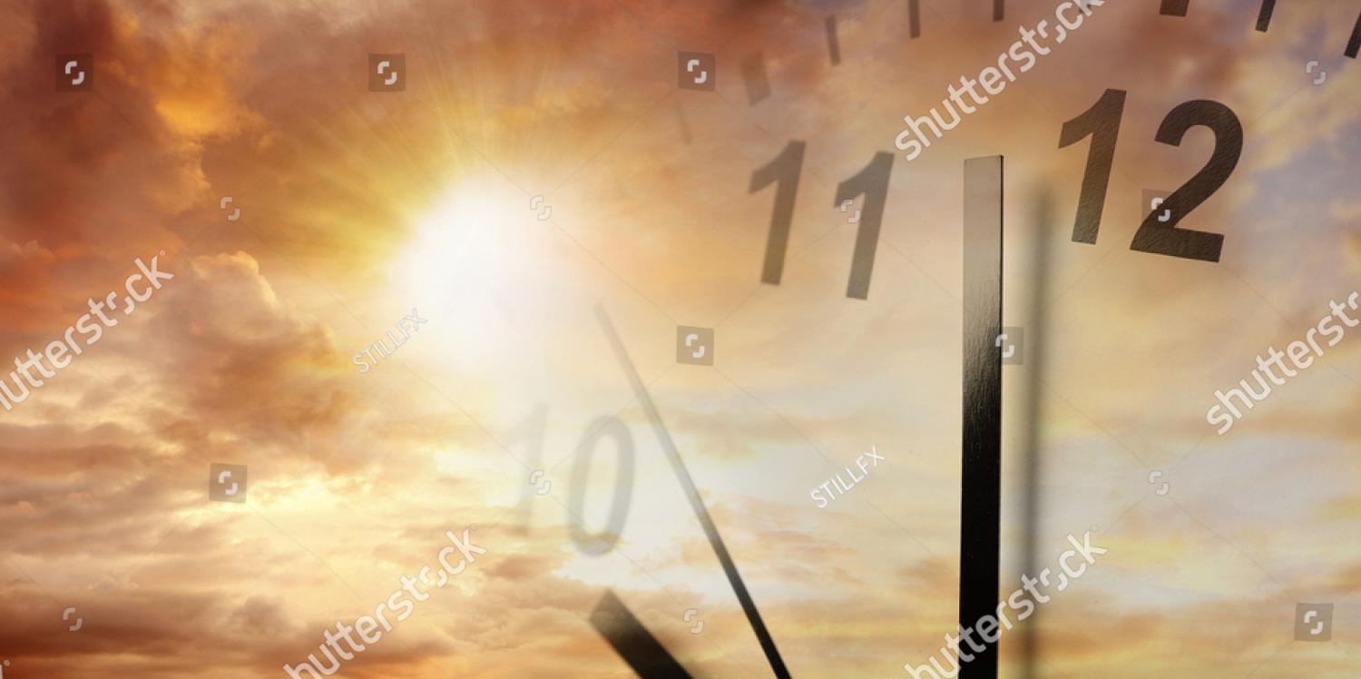A clock face over a sunrise sky